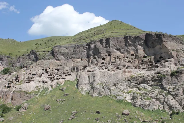 Yeşil yamacın üzerindeki kayada Vardzia mağara şehri